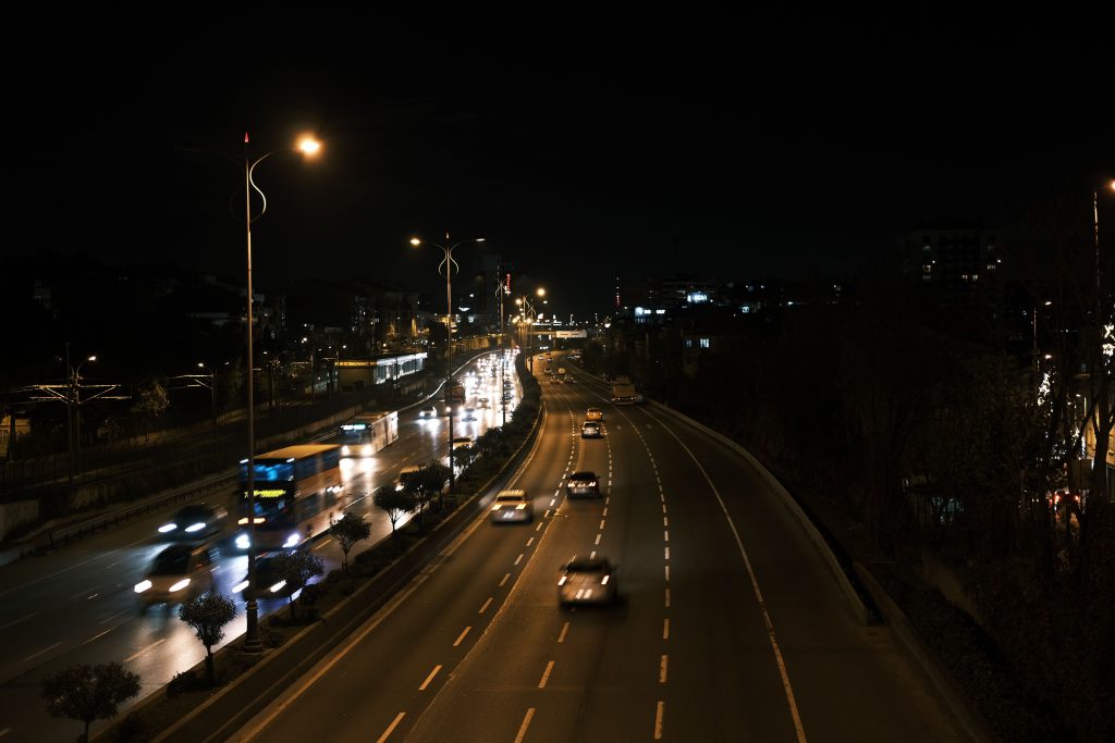 A busy urban expressway captured at night with moving vehicles and streetlights.