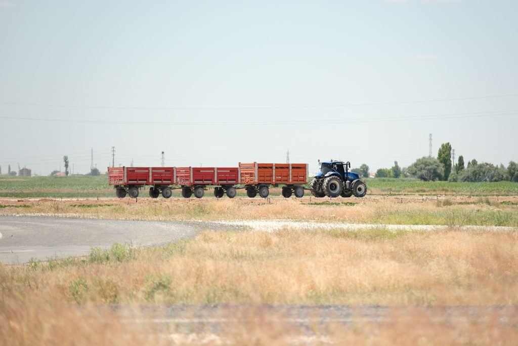 A tractor pulling multiple trailers across a rural field in Aksaray, Türkiye.